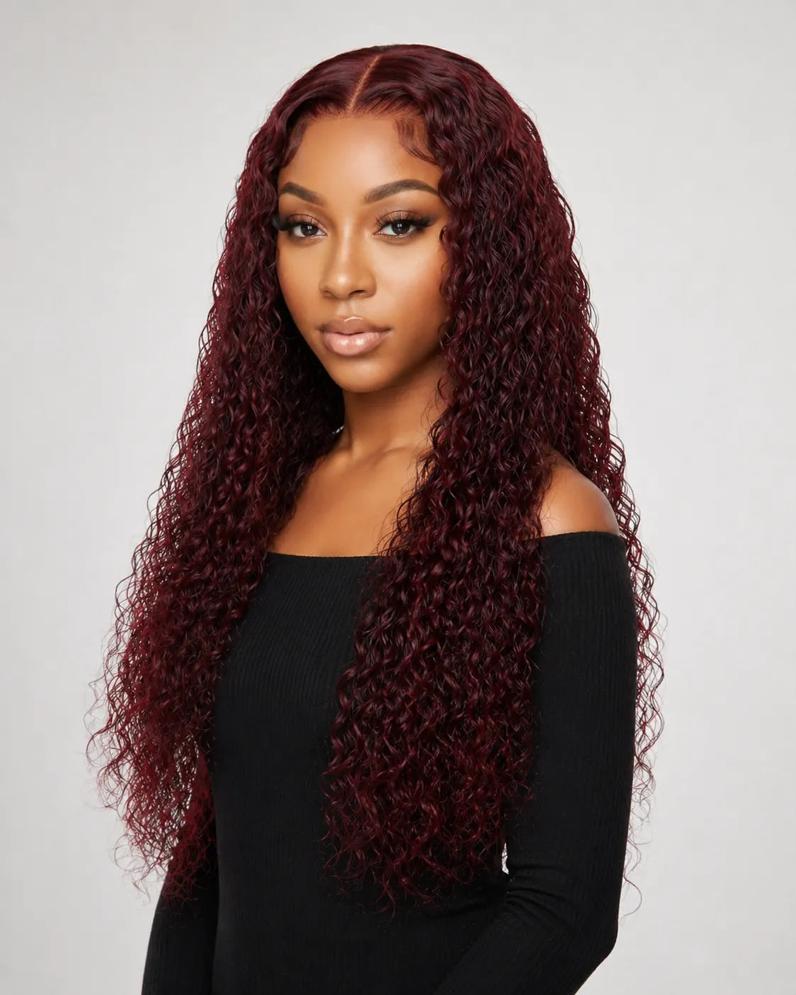 Woman with long, curly burgundy hair wearing a black top against a light gray background