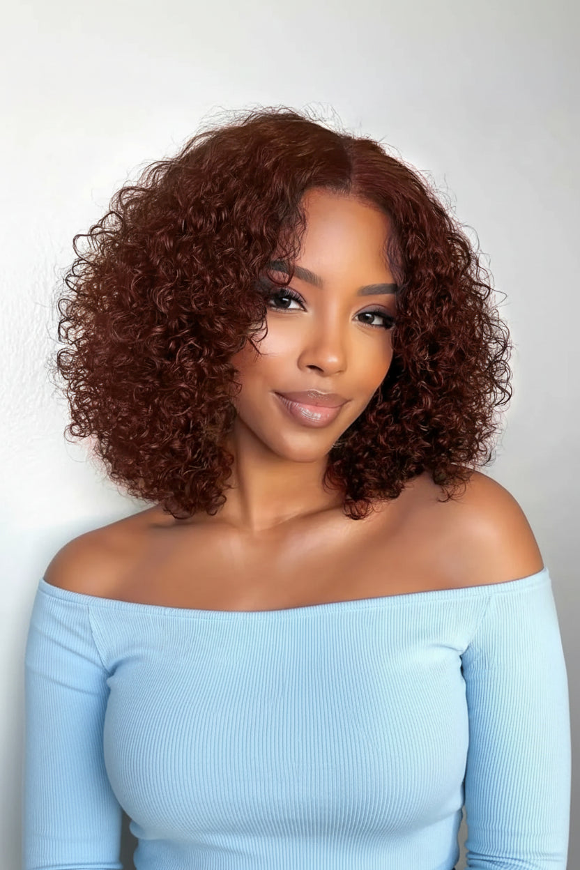 Woman with curly hair wearing an off-shoulder light blue top against a plain background